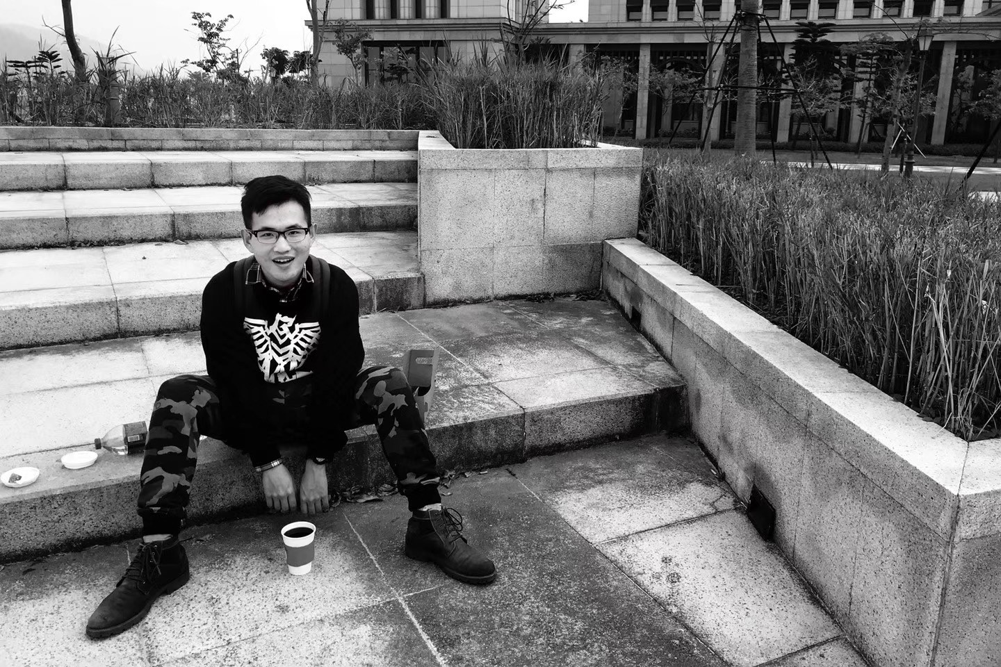 Kyle as a student, sitting on the steps of a rooftop garden