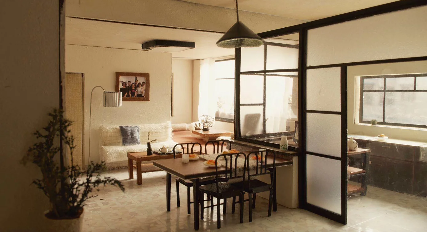 A small studio interior: a long wooden table and a glass partition